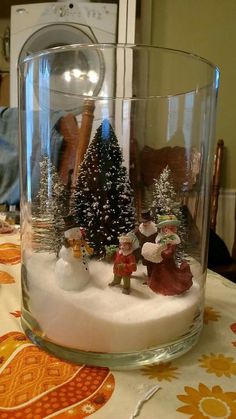 a glass bowl with snow and christmas trees in it on top of a dining room table