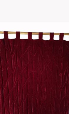 a red curtain hanging on the side of a wooden rail in front of a white wall