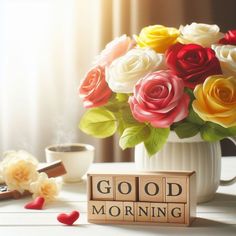 a vase filled with colorful roses next to a sign that says good morning