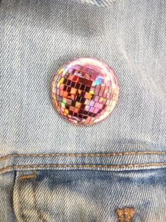 a button that is in the back pocket of a jean jacket with some sequins on it