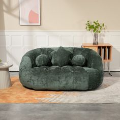 a large green couch sitting on top of a wooden floor next to a table and chair