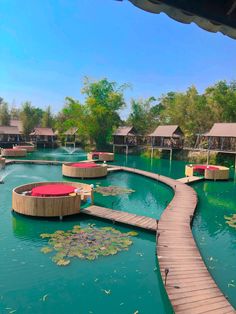 there is a wooden walkway going across the water to some huts on stilts that are floating in the water