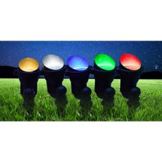 four traffic lights sitting in the grass at night