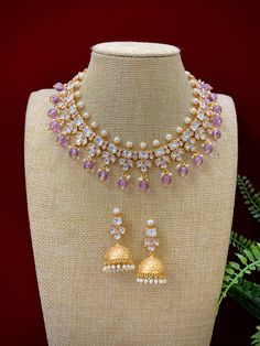 This elegant Robin tyanni kundan choker/necklace is gold-plated with tyanni kundan work and a pearl neckline. The piece is finished with lavender/lilac crystal drops and matching jhumki, all embellished with traditional kundan work. Its length is about 2 inches, with a secure push-back closure. Elegant Purple Kundan Necklace For Festive Occasions, Elegant Purple Kundan Necklace As Gift, Elegant Purple Kundan Necklace For Wedding, Elegant Purple Meenakari Jewelry, Festive Purple Kundan Necklace, Festive Purple Necklace For Wedding, Purple Kundan Necklace Gift, Purple Kundan Necklace For Gifting, Kundan Choker Necklace