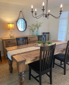 a dining room table with chairs and a mirror on the wall