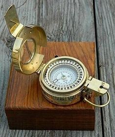 an antique brass compass on a wooden stand