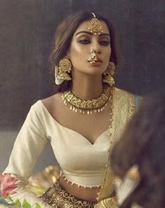 a woman in a white outfit with gold jewelry