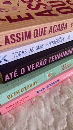 four books stacked on top of each other in front of a white bed spreader