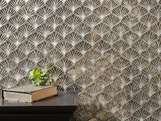 a table with a book and plant on top of it next to a wallpaper