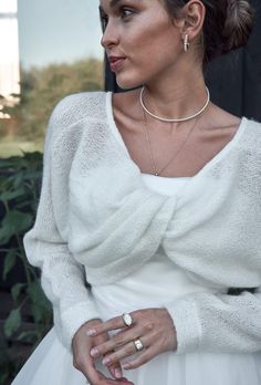 a woman wearing a white dress and jewelry