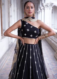 This look features a midnight black lehenga set. The lehenga has lines of gota and mirror work bootis descending into sequin & zari embroidered tiered borders. Teamed with a one shoulder blouse with pearl and mirror embellishments. A net dupatta with matching bootis and scallop border completes the look. Cancan & pockets are included. Composition: Blouse - Viscose georgette, lehenga -Viscose georgette ,Dupatta - Soft net Care: Dry Clean Only and Vacuum Storage This product can be customised for colour, sleeves, length of blouse and neck design Delivery : 2 weeks as the product is hand crafted. For more information and sizes please contact fabiliciousfashion@gmail.com or visit our Copenhagen studio.About the Designer : Renee Label was created in 2013,by the talented sister duo Pooja and Kar Black Mirror Work Dress, Black Mirror Work Lehenga, Lehnga Ideas, Shaadi Outfits, Black Dress With Pearls, Sequin Lehenga, Mirror Work Lehenga, Indian Bridesmaid Dresses, Sangeet Outfit