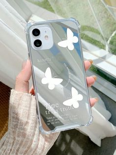 a woman holding up her phone case with butterflies on it