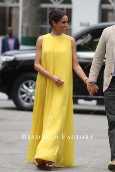 a woman in a yellow dress and a man in a suit walking down the street