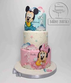 a three tiered cake with mickey mouse on it's top and the number one