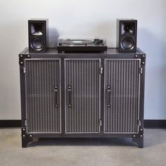 an entertainment center with speakers and a record player on it's sideboard, in front of a wall