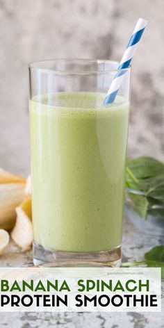 a green smoothie in a glass with a blue and white striped straw next to it