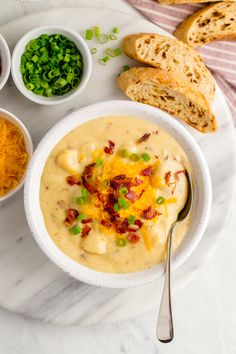 a white bowl filled with soup next to bowls of vegetables and bread on a table