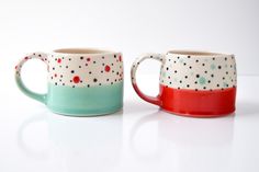 two coffee mugs sitting next to each other on a white counter top with red, green and blue designs