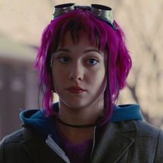 a woman with pink hair and goggles on her head is staring at the camera