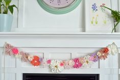 there is a clock on the mantle with paper flowers hanging from it's sides