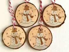 three wooden ornaments with snowmen on them hanging from red and white striped twine