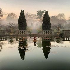 a pond surrounded by trees and bushes in the middle of a park with water reflecting it's reflection