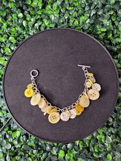 a bracelet with buttons on it sitting on top of a black table next to green plants