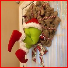 the grinch is hanging on the front door with his head stuck into the wreath