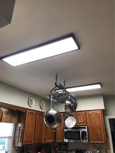 an overhead light fixture in a kitchen with wooden cabinets and stainless steel appliances on the counter