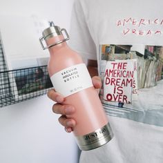 a person wearing a white shirt holding a pink bottle