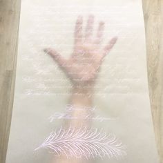 a person's hand on top of a piece of paper with writing behind it