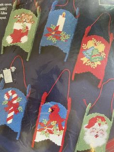 cross - stitch christmas ornaments are displayed on a plastic sheet in the shape of santa's sleighs