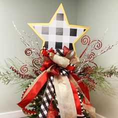 a christmas tree decorated with red, white and gold ribbons in front of a star