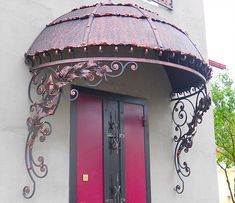 a red door is in front of a white building with ornate iron work on it