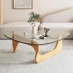 a glass coffee table with wooden legs in a living room next to a white couch