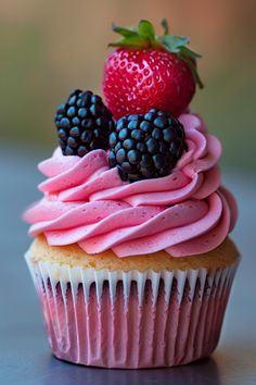 a cupcake with pink frosting and blackberries on top