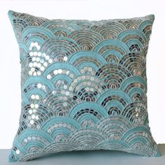 a blue pillow with silver sequins on the front and back, sitting on a table