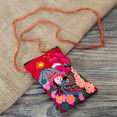 a small red purse sitting on top of a wooden table next to an orange string