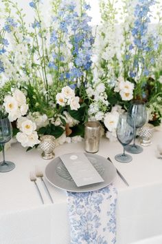 the table is set with blue and white floral centerpieces, silverware, and napkins