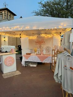 an outdoor tent with clothes and t - shirts on display