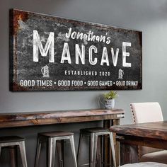 a wooden sign hanging on the side of a wall next to bar stools and a table