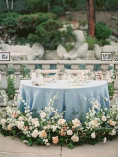 an outdoor table with flowers and candles on it