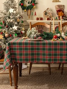 the table is set for christmas dinner with plaid cloth on it and candles in the center