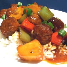 a white plate topped with rice and meat covered in gravy next to veggies