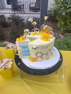 a cake sitting on top of a table covered in yellow and white frosted decorations