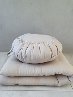 three pillows stacked on top of each other in front of a white wall and floor