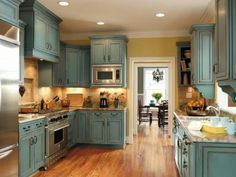 a large kitchen with blue cabinets and wood flooring, along with stainless steel appliances