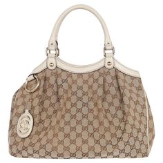 Authentic, pre-loved Gucci Sukey GG monogram canvas top handle bag. The Sukey top handle bag keeps all your necessities in check. Features beige/ebony original Gucci canvas with beige leather trim, light gold hardware, detachable interlocking GG leather tag, double rolled handles, snap closure, reinforced leather corners, snap sides, large interior with zipper pockets. Add your book, iPad, phone, cosmetic case, wallet, keys, and more. You're going to love this bag. Authenticity model code: 211944 520981 Handle drop: 6." 13"L x 5"W x 11.0"H Condition Gently Used Exterior scuff, stains or marks, corner rub, the interior has signs of use and stains, the straps are strong at the base, the interior closure works properly, side snap is broken which does not affect the use. Please look at every d Louis Vuitton Crossbody Bag, Louis Vuitton Crossbody, Weekend Travel Bags, Gg Monogram, Leather Tag, Cute Nike Shoes, Cute Nikes, Baby Diaper Bags, Handle Bag