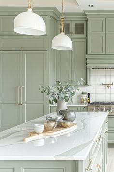 a large kitchen with green cabinets and white counter tops, along with an island in the middle