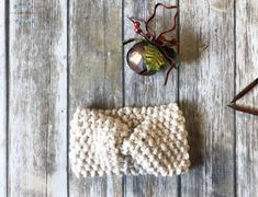 a knitted headband next to an ornament on a wooden table with other items